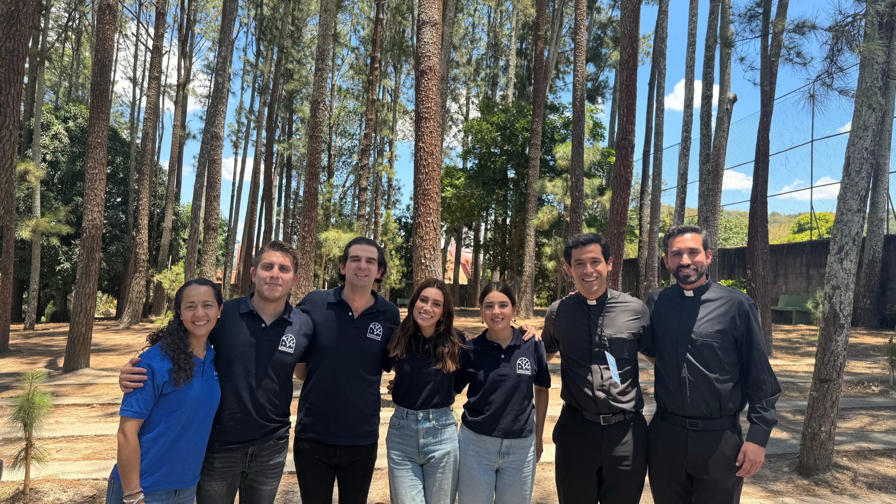 Equipo AWAKEN con dos sacerdotes en un bosque de pinos